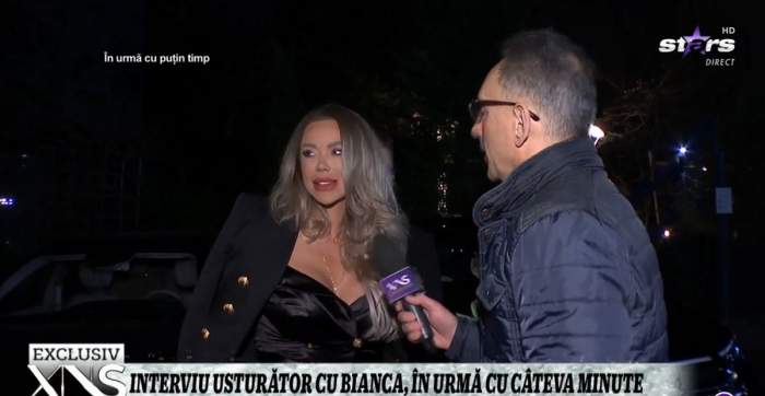 Bianca Drăgușanu poartă o rochie neagră, iar pe deasupra are un blazer în aceeași nuanță. Vedeta dă un interviu reporterului de la Xtra Night Show.