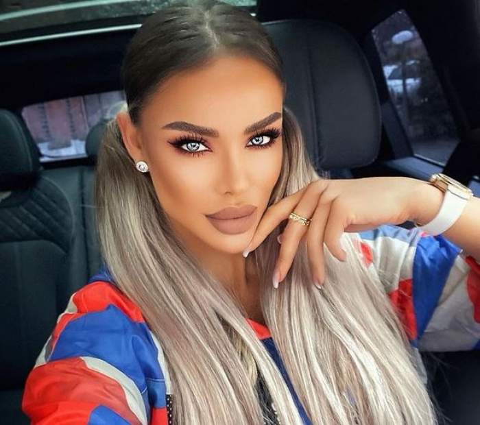 Bianca Drăgușanu se află în mașină. Vedeta își face un selfie și poartă o bluză de trening colorată în alb, roșu și albastru.