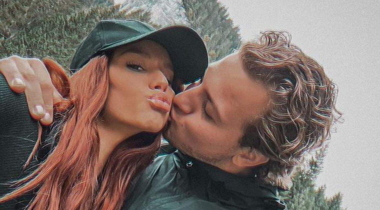 Carmen Grebenișan și Alex Militaru într-un selfie. Iubitul ei o sărută pe obraz, iar ea ține buzele țuguiate și poartă o șapcă neagră pe cap.