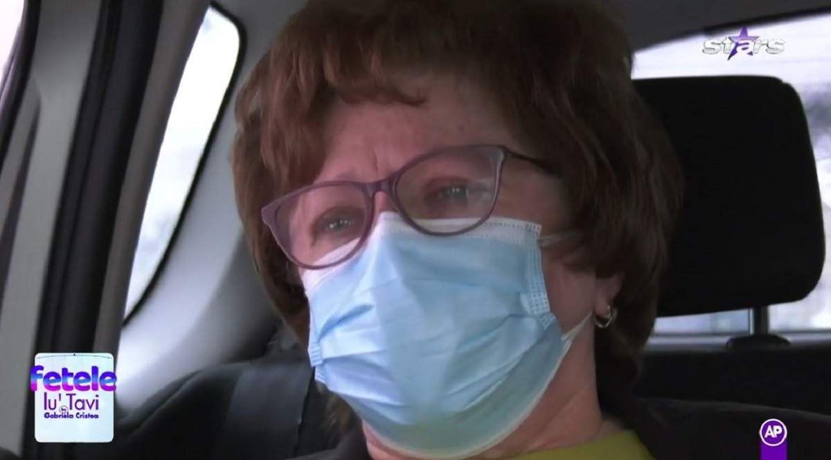 Mama lui Tavi Clonda poartă ochelari de vedere și mască de protecție. Elena Clonda are ochii în lacrimi și e în mașină.