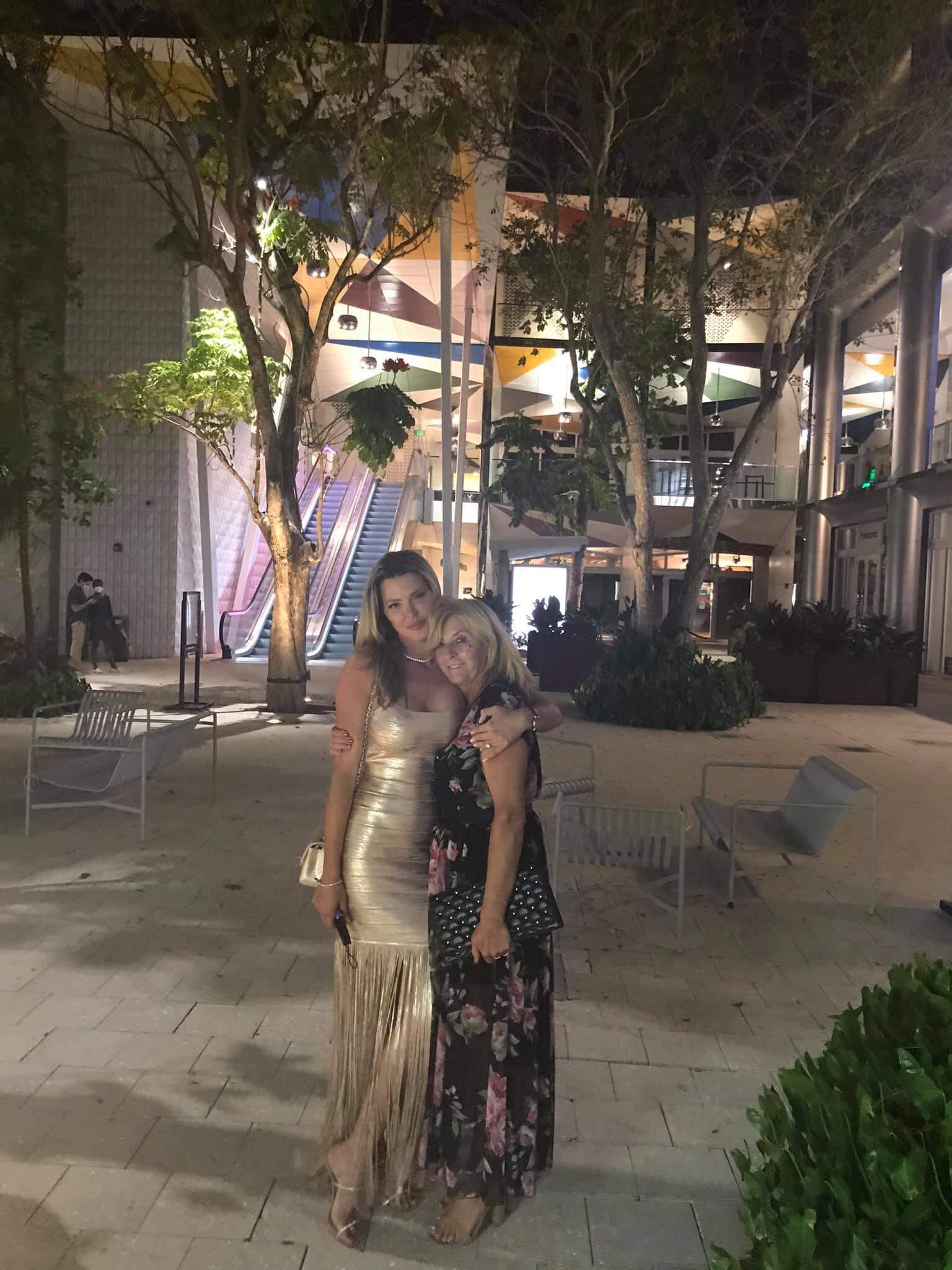 Alina Vidican și mama ei în Miami. Vedeta poartă o rochie aurie, iar mama ei una neagră cu flori colorate și se îmbrățișează.