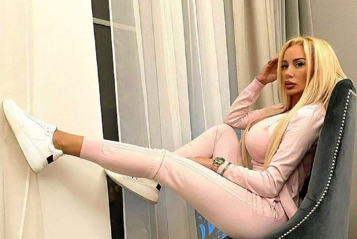 Simona Trașcă stă pe un fotoliu gri. Vedeta poartă un trening roz și adidași albi.