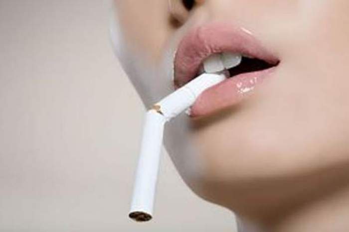 O femeie care ține în gură o țigară ruptă