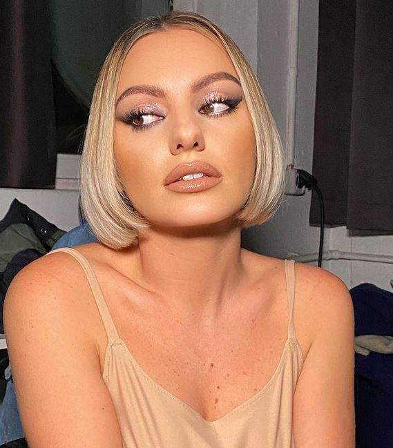 Alexandra Stan poartă un maiou cred. Vedeta are gura întredeschisă și privește într-o parte.