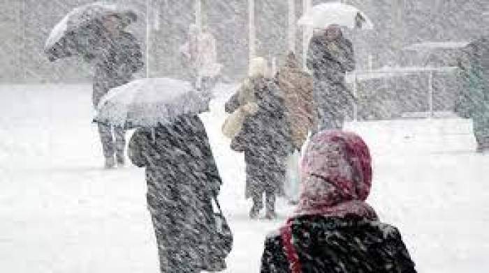 Mai mulți oameni, îmbrăcați de iarnă, aleargă prin zăpadă, cu umbrelele în mână