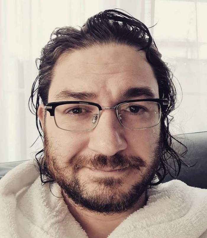 Florin Dumitrescu și face un selfie. Chef-ul e îmbrăcat în halat de baie alb și poartă ochelari de vedere.