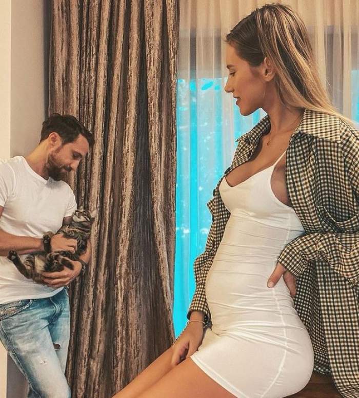 Dani Oțil ține în brațe o pisică, iar Gabriela Prisăcariu poartă o rochie albă, mulată, iar pe deasupra un sacou în pătrățele. Blondina privește în jos și zâmbește.