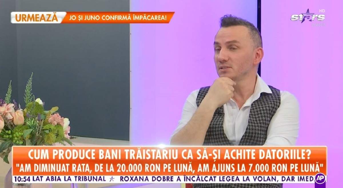 Mihai Trăistariu poartă o cămășă albă și o vestă în pătrățele alb-negru pe deasupra. Artistul dă un interviu pentru Antena Stars.