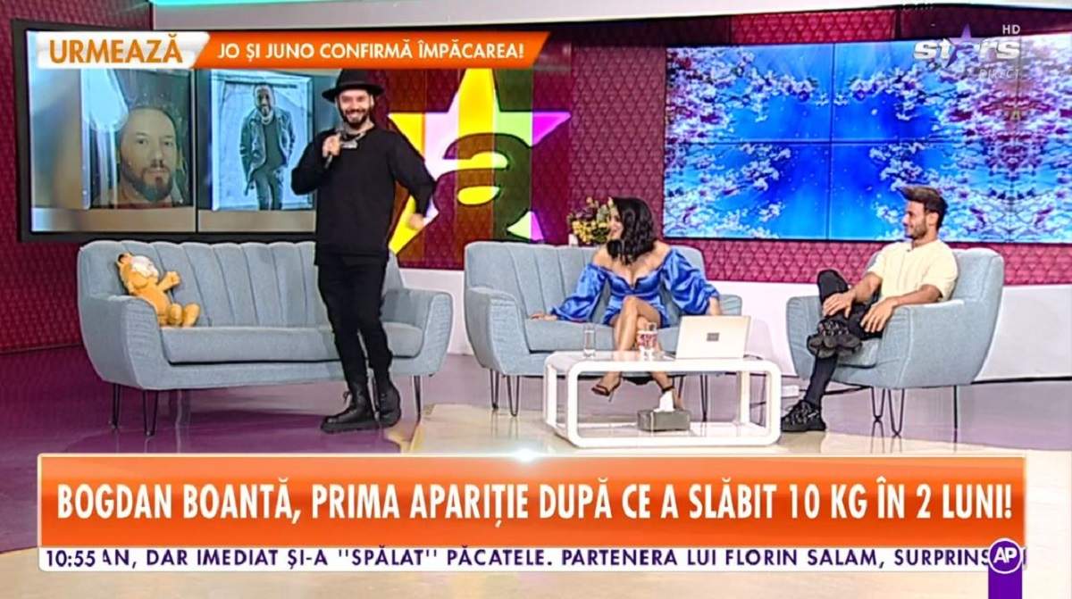 Bogdan Boantă e la Antena Stars. Dansatorul e îmbrăcat în bluză și pantaloni negri și are pe cap o pălărie neagră. Coregraful stă în picioare și ține microfonul în mână.
