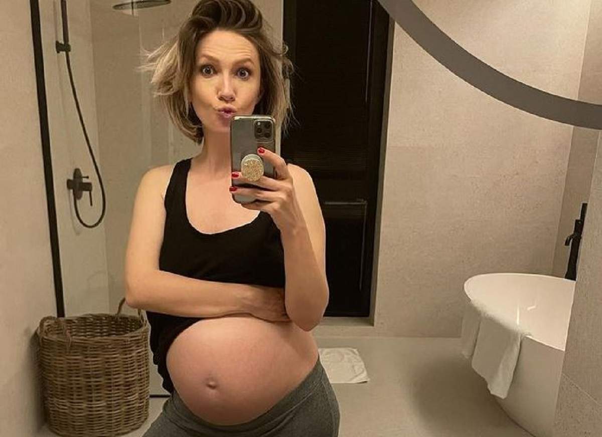 Adela Popescu e în baie și își face o poză cu telefonul mobil, în oglindă. Vedeta poartă un maiou negru și are burtica de gravidă descoperită.