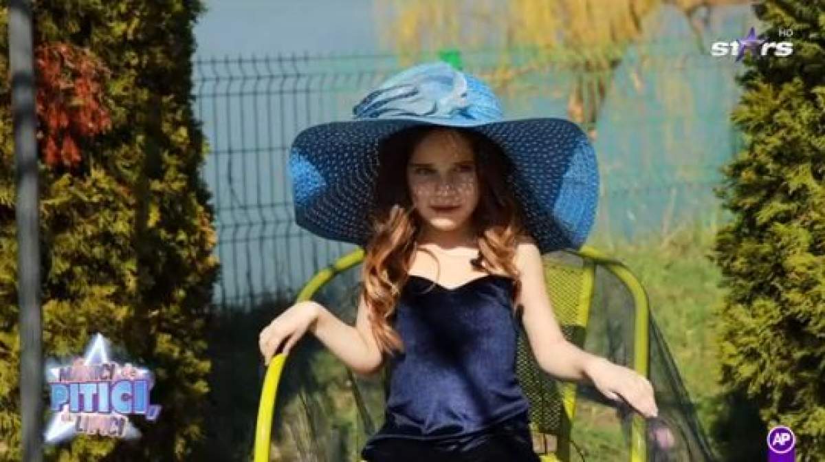 Isabela, îmbrăcată în albastru, cu pălărie de soare pe cap