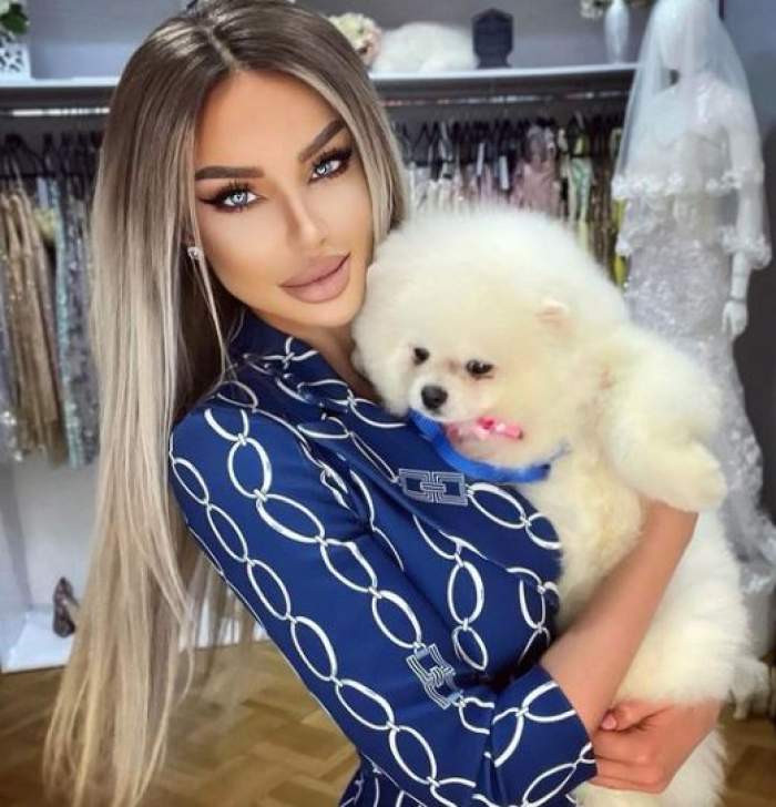 Bianca Drăgușanu în costum albastru, cu un câine în brațe.