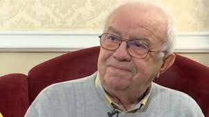 Alexandru Arșinel, zâmbitor, îmbrăcat în gri