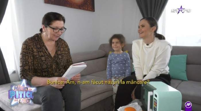 Cristina Șișcanu, mama ei și fiica sa stau pe o canapea. Vedeta poartă o bluză albă, mama ei una maro cu model negru și citește dintr-un caiet, iar micuța Petra poartă o bluză bleu cu model alb.