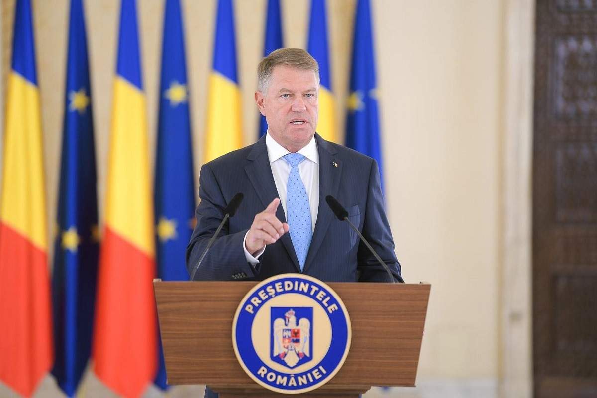 Klaus Iohannis ține un discurs. Președinte poartă cămașă albă, cravată bleu și sacou albastru.