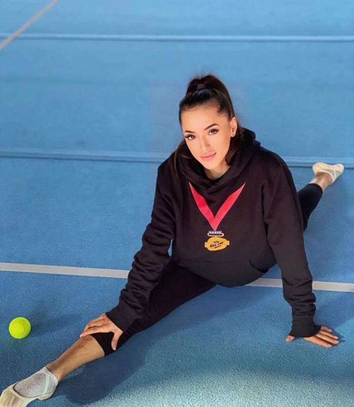 Larisa Iordache este pe saltea, in sala, in pozitia spagatului