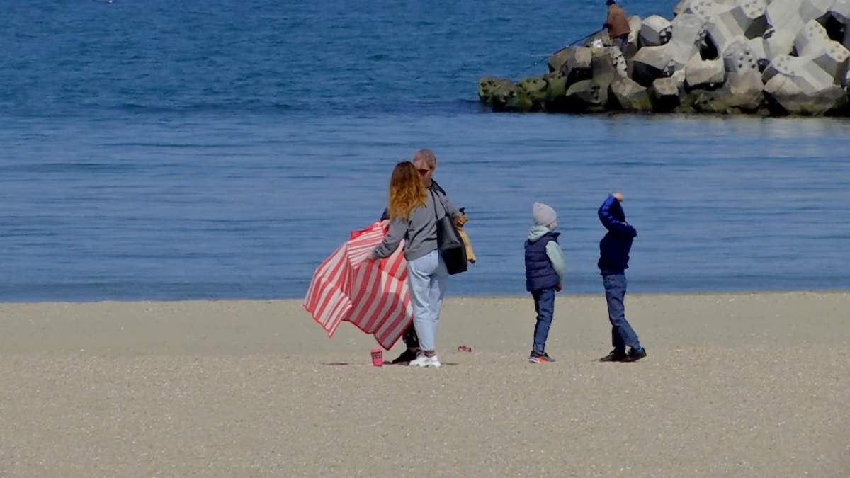o femeie cu doi copii pe plaja