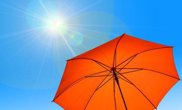 Un cer senin cu soare și o umbrelă portocalie
