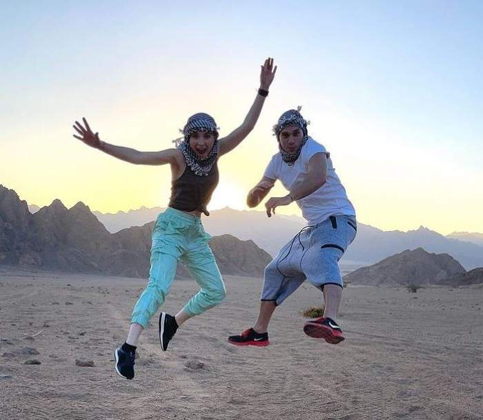 O poză cu Cristina Ciobănașu și Vlad Gherman în vacanță. Amândoi sar în aer, poartă haine sport și au pe cap eșarfe.
