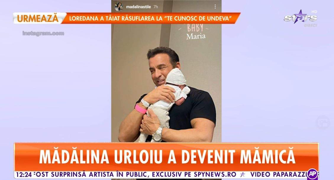 Soțul Mădălinei Urloiu, Frank Stile, o ține în brațe pe fiica lor. Medicul poartă un tricou negru.