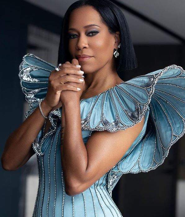 Regina King poartă rochia bleu de la Oscar 2021. Vedeta își ține mâinile la nivelul bărbiei.