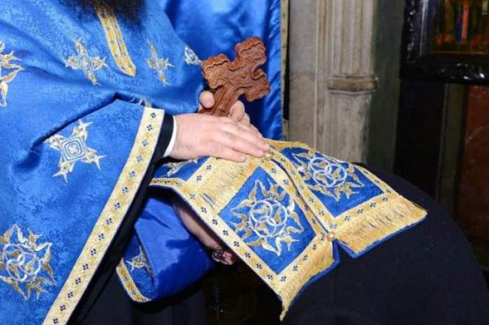 Un preot în haine bisericești albaștri spovedește o persoană