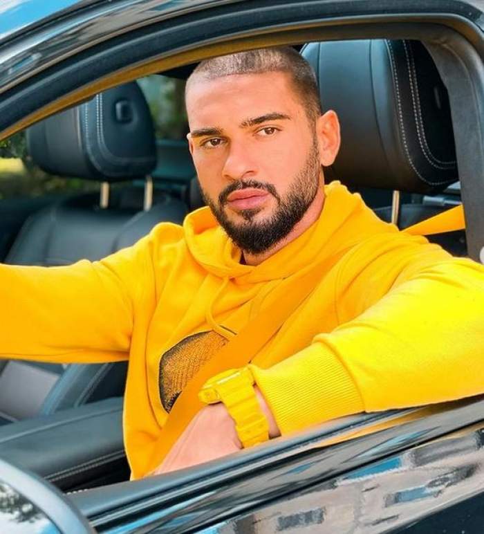 Dorian Popa e în mașină. Artistul poartă un hanorac galben.