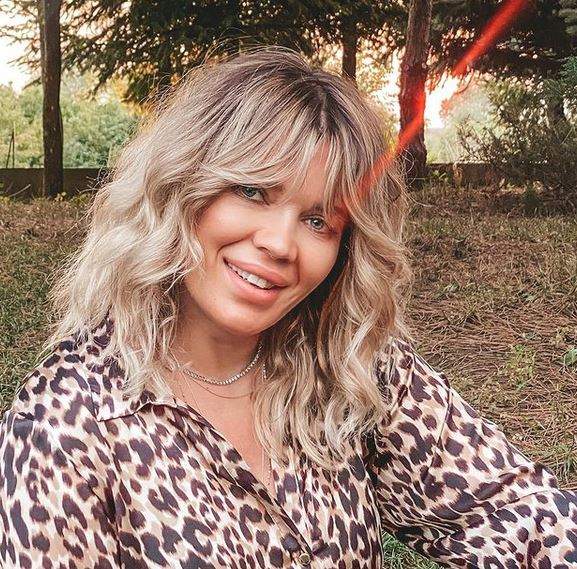 Gina Pistol e îmbrăcată într-o cămașă cu animal print, stil leopard. Vedeta zâmbește larg.