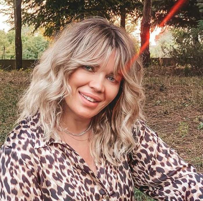 Gina Pistol e îmbrăcată într-o cămașă cu animal print, stil leopard. Vedeta zâmbește larg.