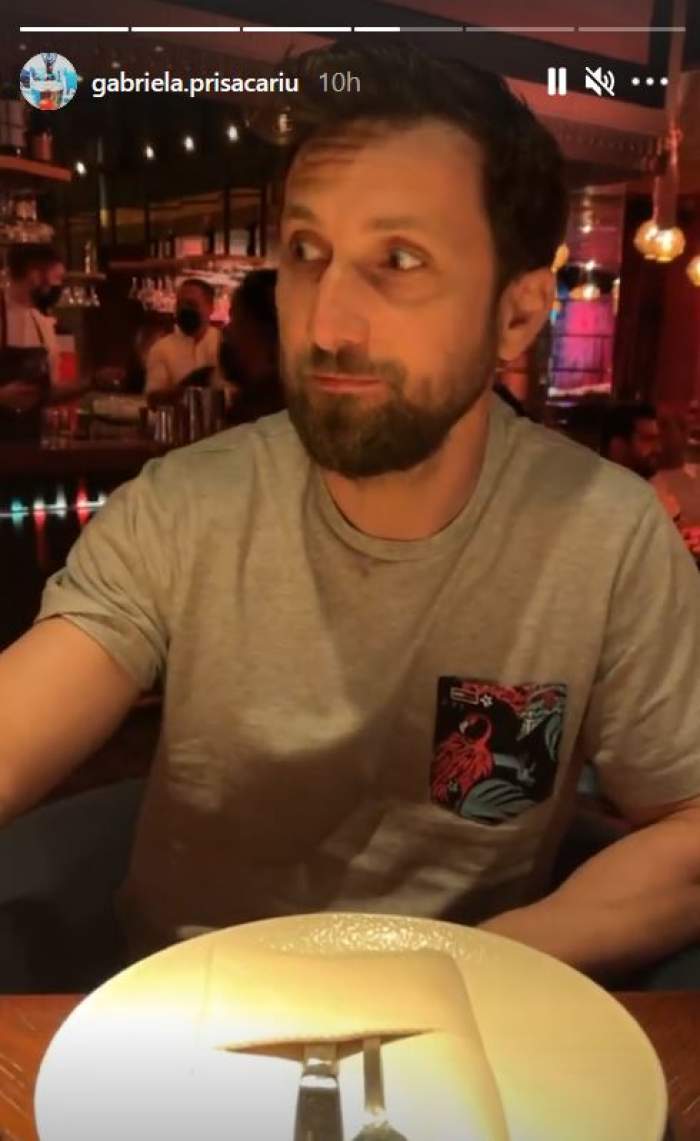 Dani Oțil e la restaurant, în Dubai. Acesta poartă un tricou gri, iar pe masă, în fața lui, e o farfurie cu niște tacâmuri pe ea.