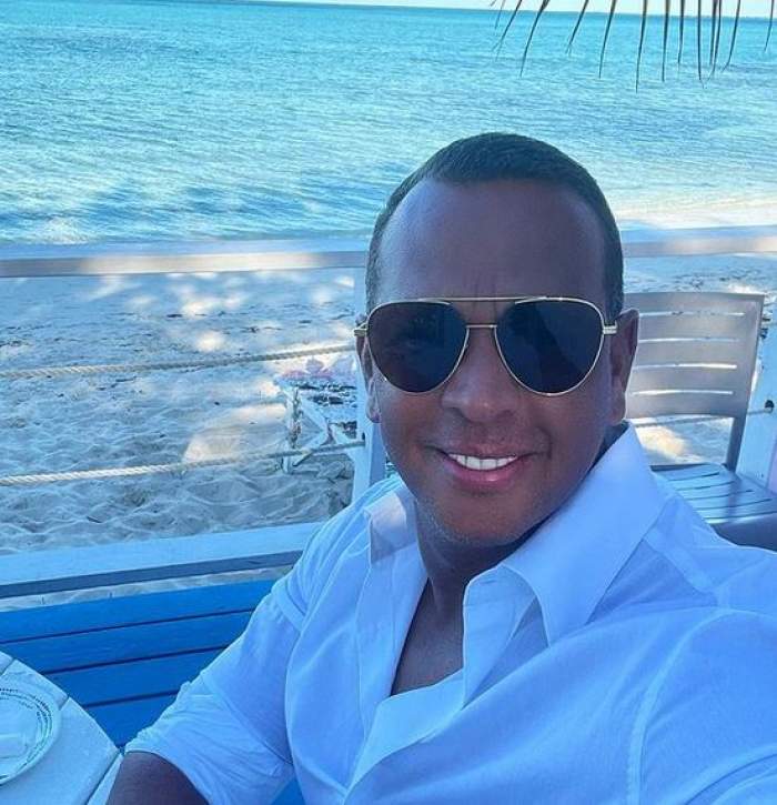 Alex Rodriguez își face un selfie la plajă. Sportivul zâmbește, poartă ochelari de soare și e îmbrăcat cu o cămașă albă.
