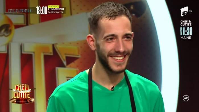Luca Pintea este la Chefi la cuțite. Concurentul poartă tricou verde și șorț negru. Tânărul zâmbește larg.