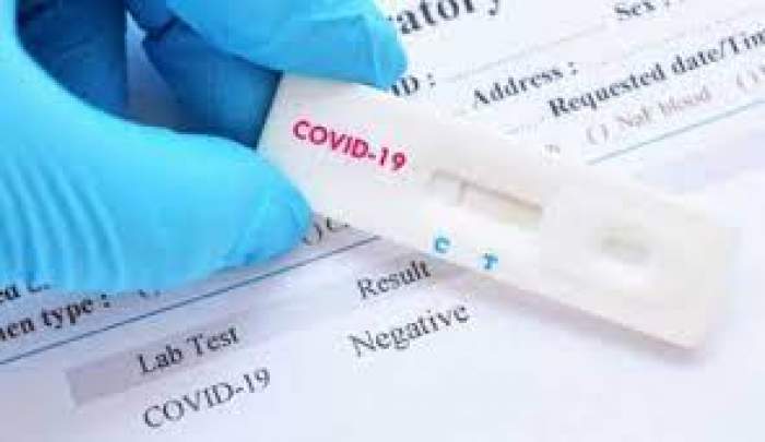 Test anti-coronavirus, ținut în mână de un medic ce poartă mânușă de protecție