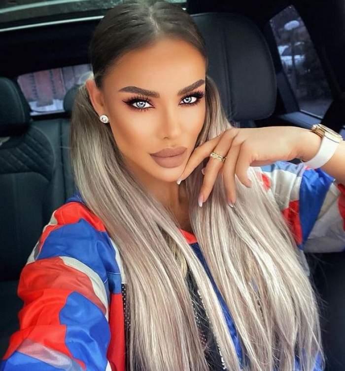 Bianca Drăgușanu se află în mașină. Vedeta își face un selfie și poartă o bluză de trening colorată în alb, roșu și albastru.