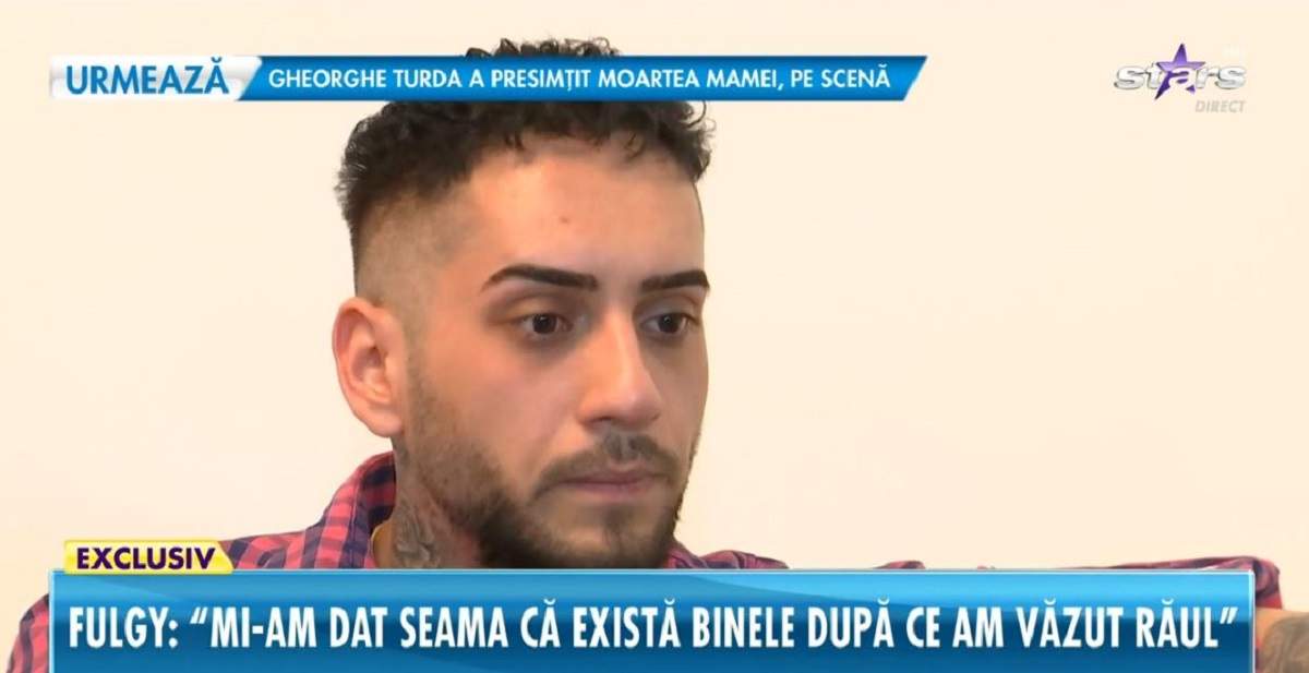 Fulgy de la Clejani dă un interviu pentru Antena Stars. Artistul poartă o cămașă în pătrățele albastre și roșii.