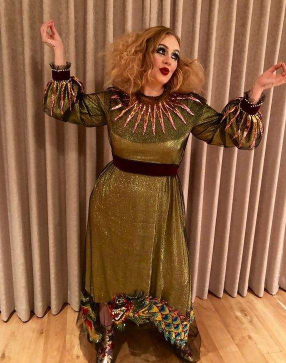 Adele poartă o rochie verde. Artista ține brațele în aer și are buzele țuguiate.