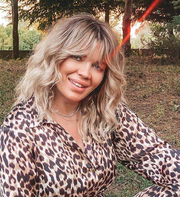 Gina Pistol e îmbrăcată într-o cămașă cu animal print, stil leopard. Vedeta zâmbește larg.