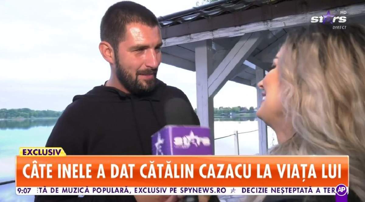 Cătălin Cazacu dă un interviu pentru Antena Stars și poartă un tricou negru. În spatele lui se vede un lac.