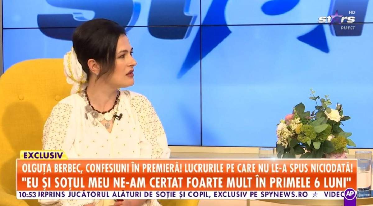Olguța Berbec oferă un interviu la Antena Stars, stând pe un fotoliu galben. Vedeta poartă o ie albă.