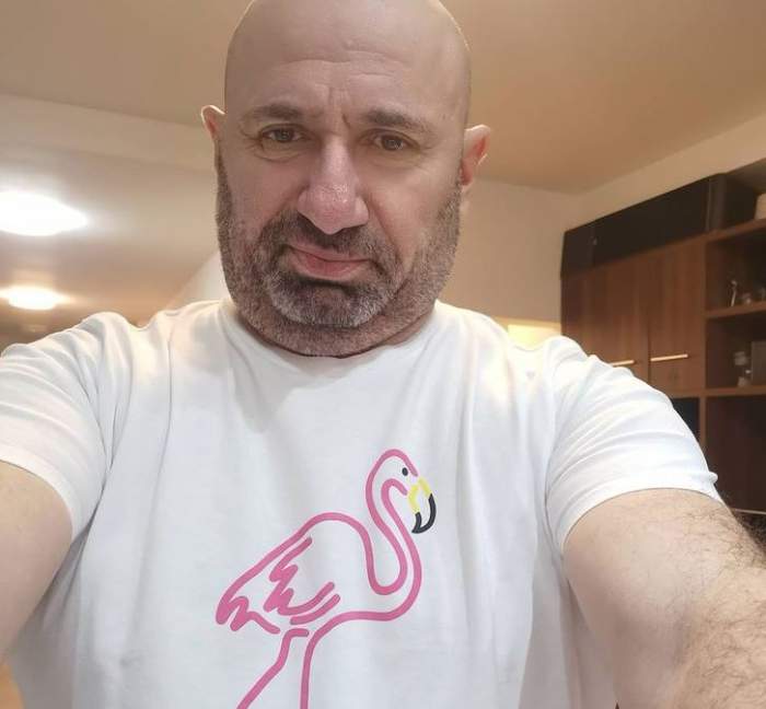 Cătălin Scărlătescu își face un selfie. Chef-ul poartă un tricou alb cu desen cu flamino roz în centru.