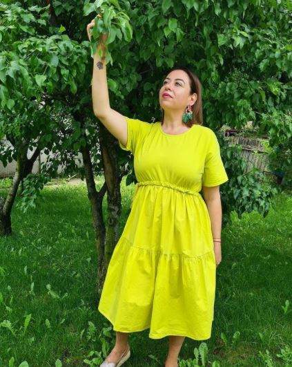 Oana Roman în rochie galbenă, în grădină.