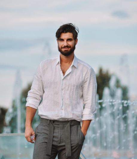 Andi Constantin cu cămașă albă și pantaloni gri.
