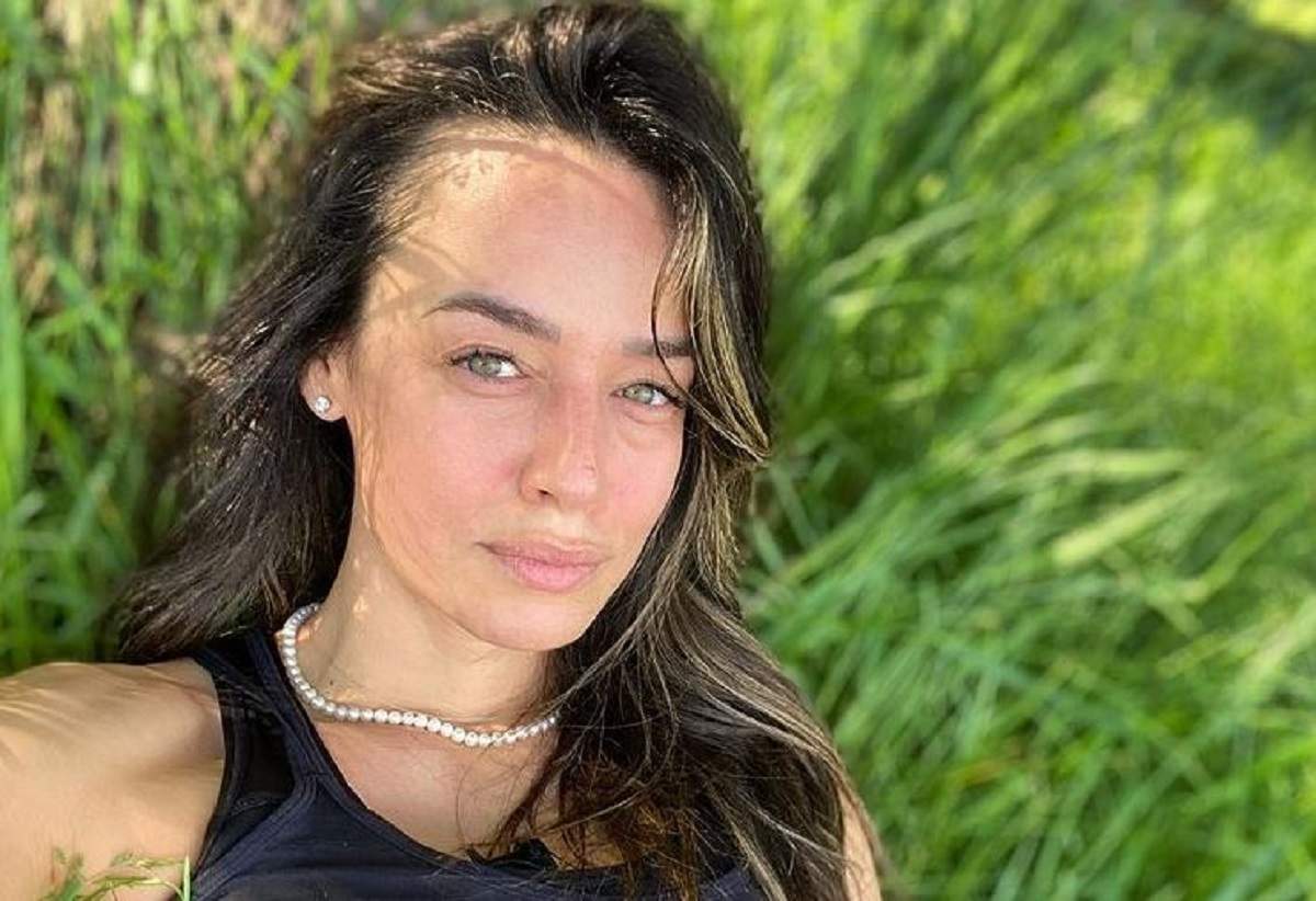 Andreea Raicu își face un selfie din iarbă și poartă maiou negru.