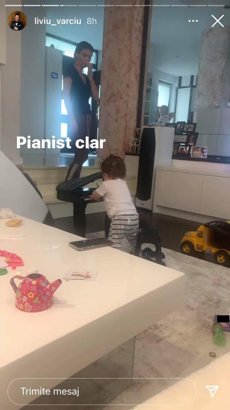 Fiul lui Liviu Vârciu stă în picioare și cântă la pian. Micuțul poartă pantaloni în dungi, tricou alb și e supravegheat de Anda Călin, mama lui.