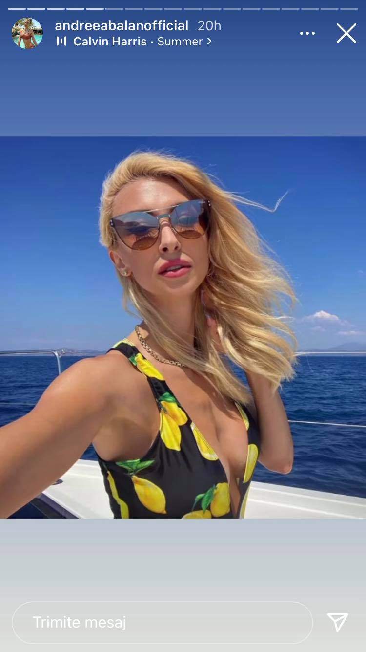 Andreea Bălan se află pe vapor, în Grecia. Artista poartă ochelari de soare și costum de baie negru cu model cu lămâi.