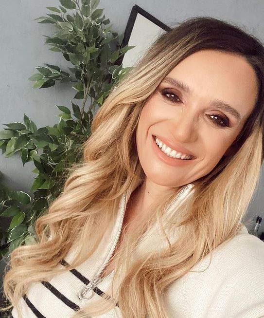 Carmen Neogiță își face un selfie în care zâmbește larg și are părul aranjat în bucle lejere.