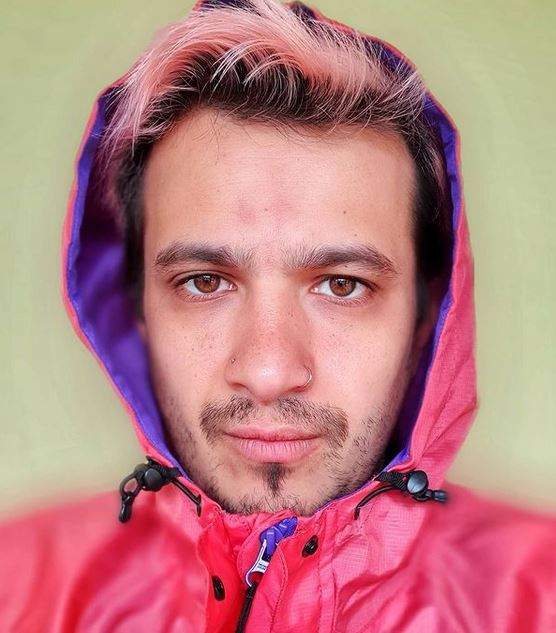 Keed poartă o geacă roz. Artistul își ține gluga pe cap și face un selfie.