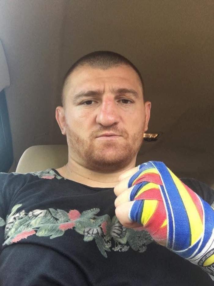 Cătălin Moroșanu e în mașină, moartă tricou negru și are mâna cu bandaje cu steagul României.