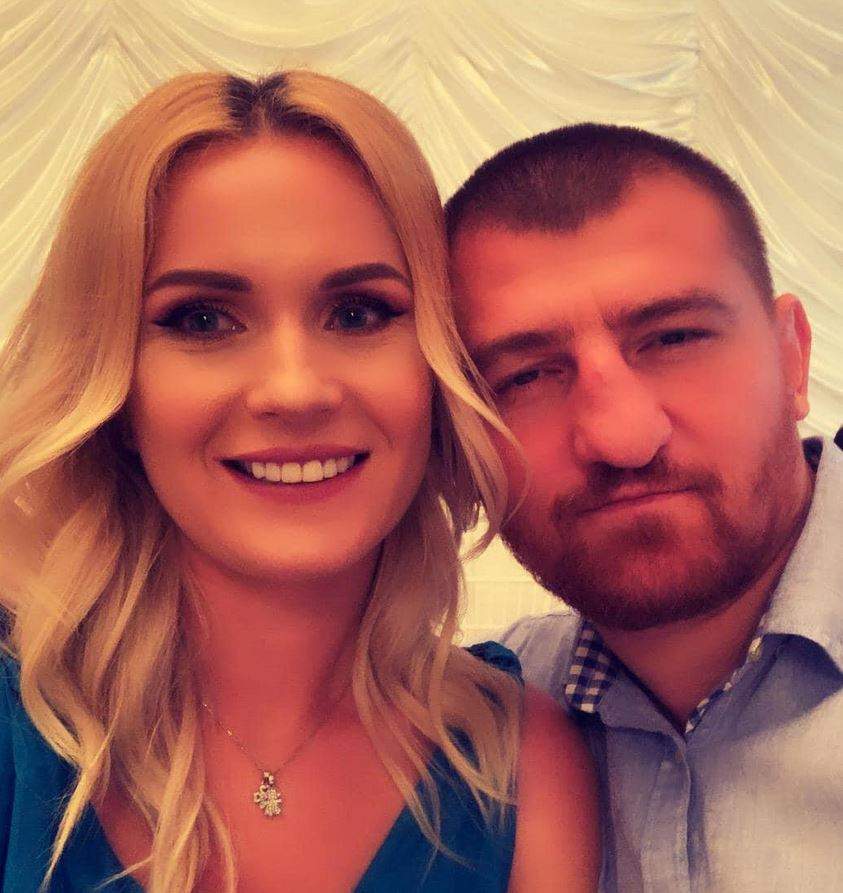 Cătălin Moroșanu și soția lui sunt la o petrecere. El poartă cămașă bleu, iar ea rochie albastră și zâmbește.