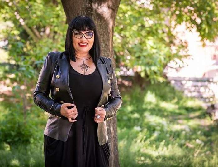 Ozana Barabancea e în parc și poartă o rochie neagră, având pe deasupra o geacă de piele neagră.